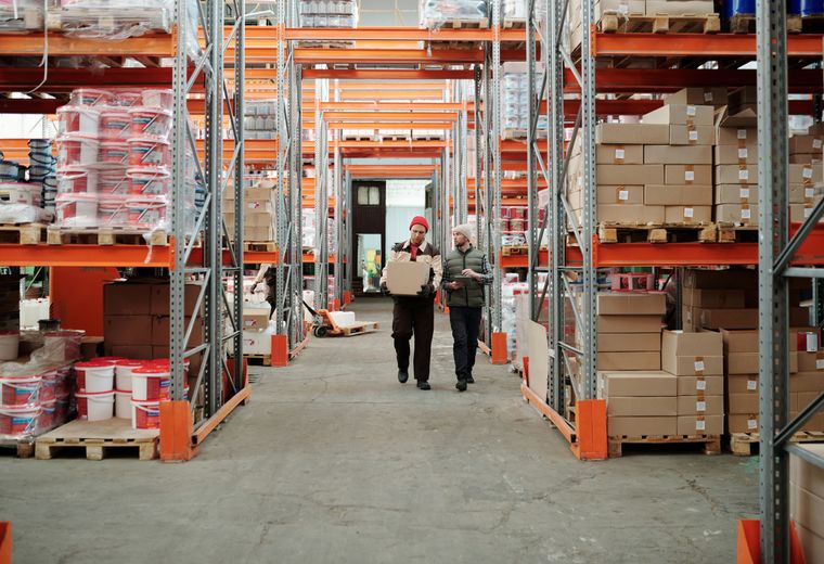 Arbetare flyttar gods mellan hyllor i ett logistiklager